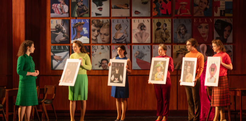 Six actors are on the stage in The Girls of Slender Means at the Lyceum in Edinburgh. 5 are holding images from the cover of a magazine to show the editor.
